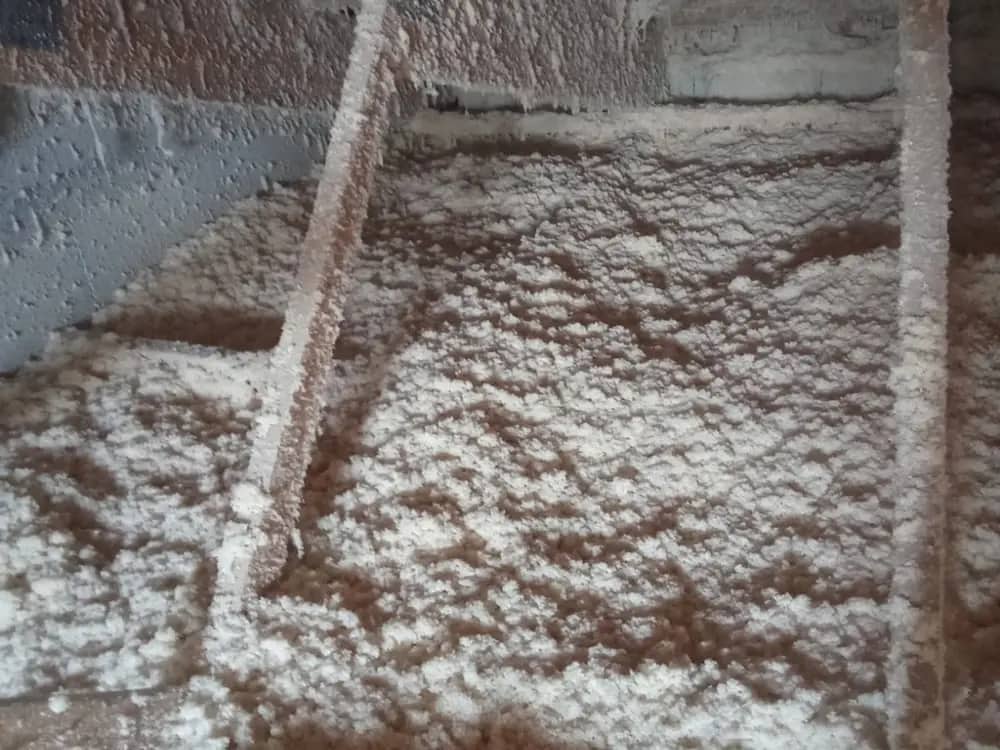 Isolant soufflé réparti sur le plancher de combles perdus, solive apparente
